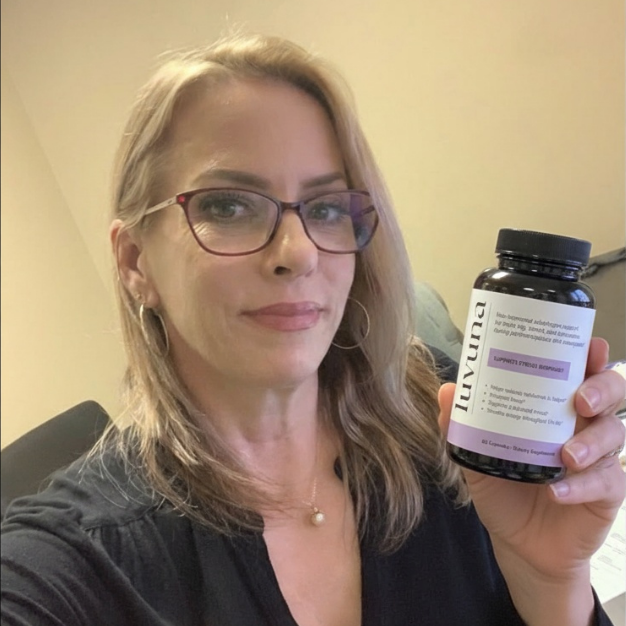 Person holding a bottle labeled 'luvuna' in an office setting.