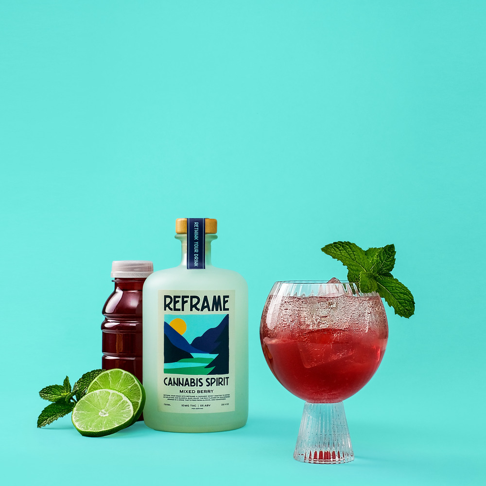 Bottles and a cocktail glass with mint and lime on a turquoise background.