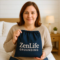 Person holding a bag labeled 'ZenLife Grounding' in a cozy bedroom setting.