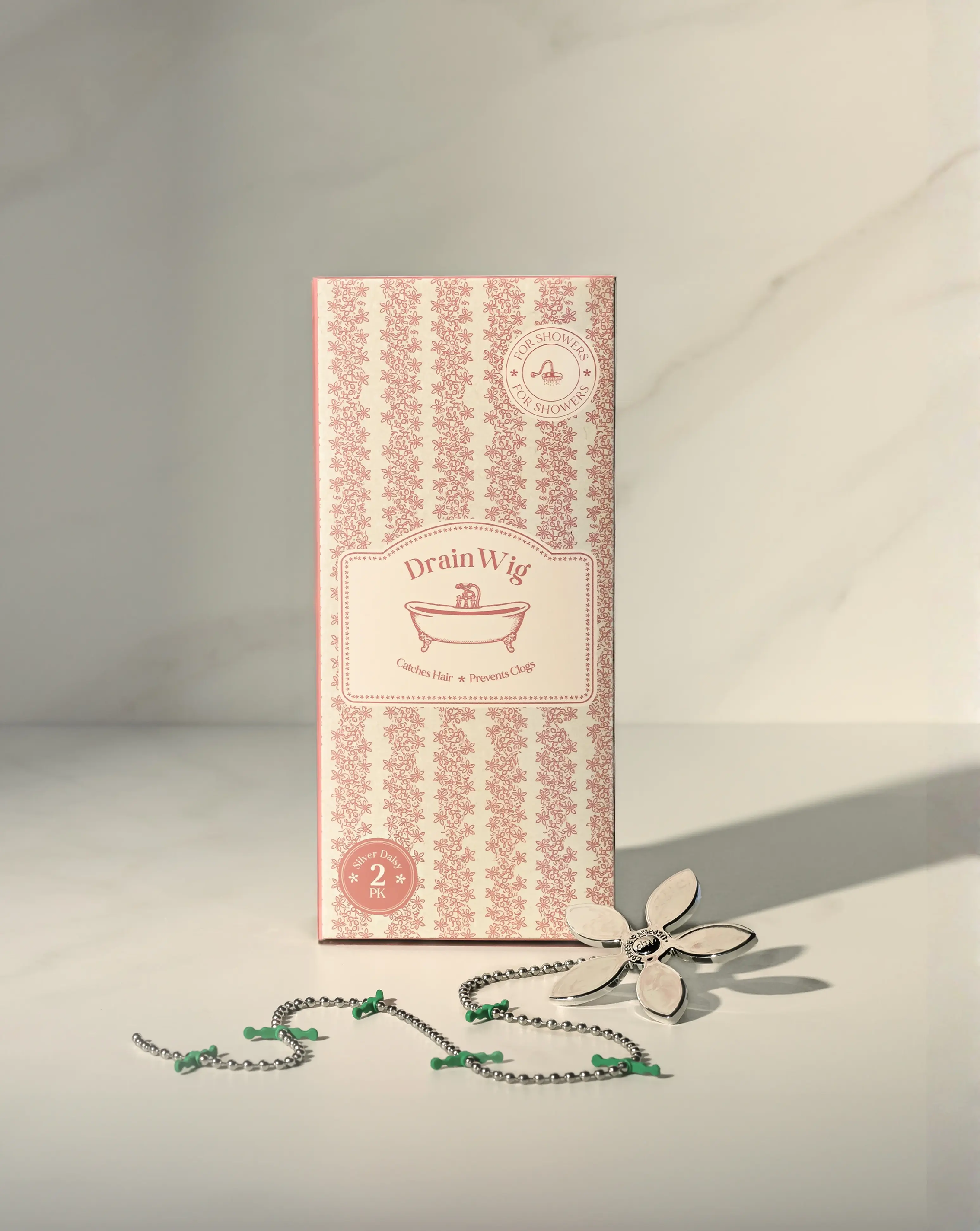 The box for a Drain Wig shower hair catcher, with the flower-topped chain product displayed in front.
