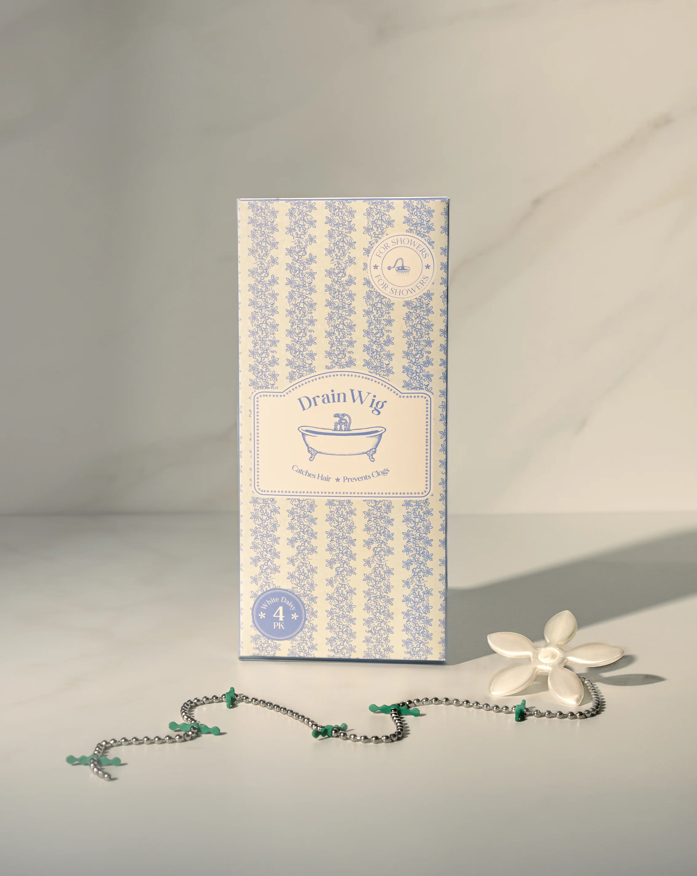 A box for Drain Wig with the flower-topped drain hair catcher chain displayed in front of it.