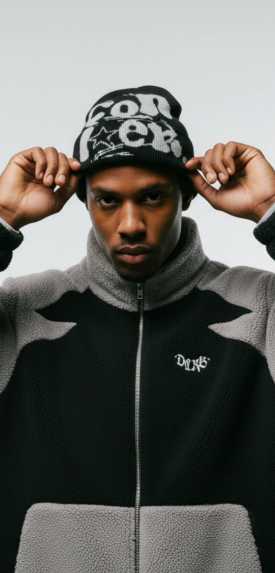 A man looks at the camera while adjusting his black and white graphic beanie.