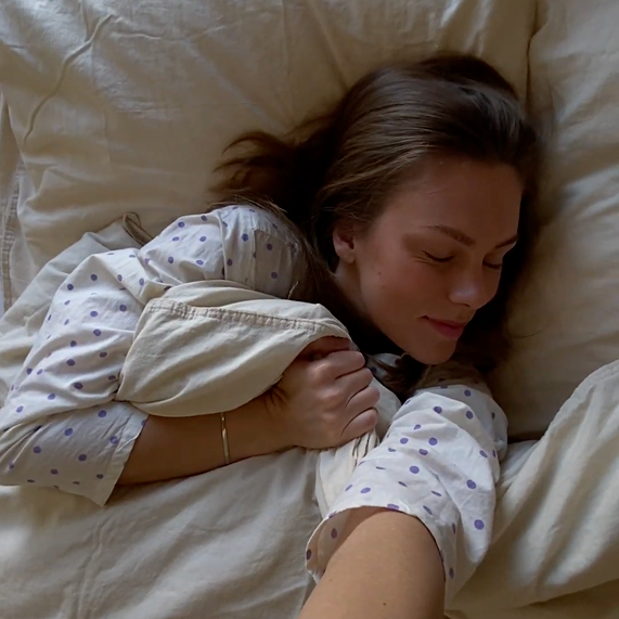 Person sleeping in bed with polka dot pajamas.