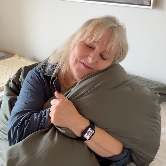 Woman hugging a pillow with a content expression.