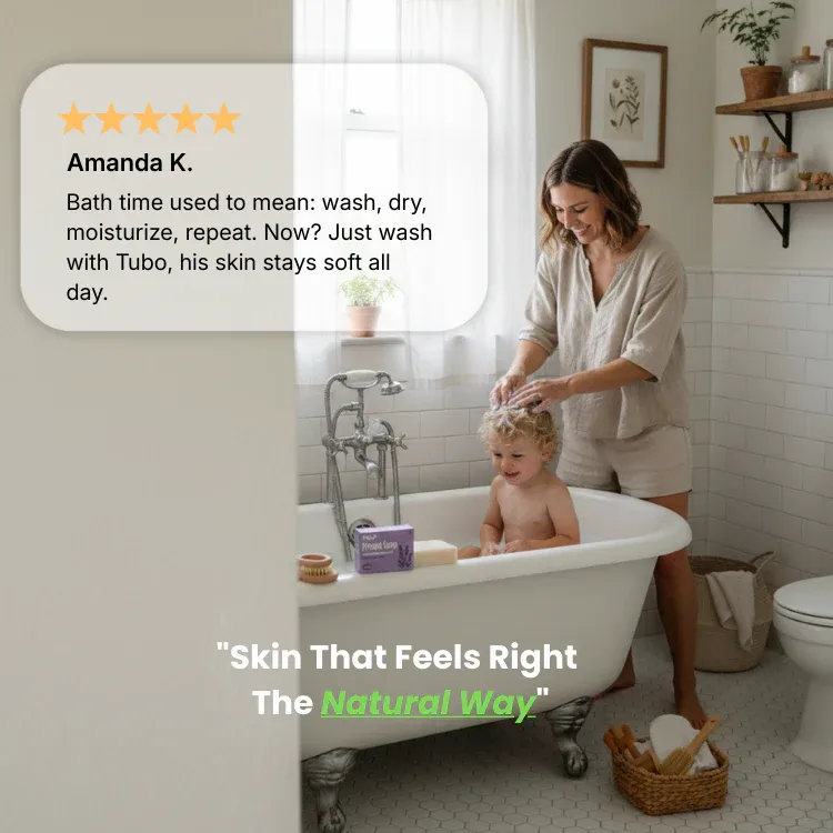 A woman washes a young child's hair while they sit smiling in a clawfoot bathtub.