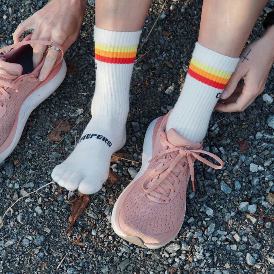Person wearing striped socks and pink shoes on gravel.