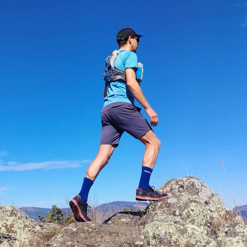 Person hiking on rocky terrain under a clear blue sky.
