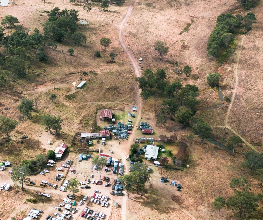 Aerial view of a rural area with scattered buildings and parked vehicles.