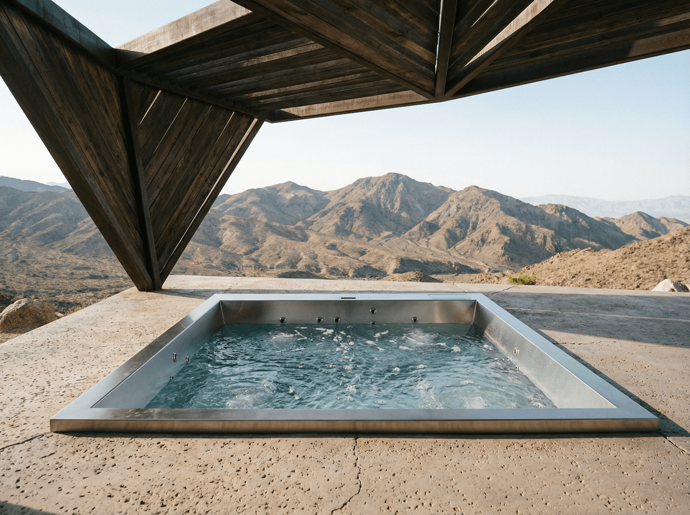 Outdoor hot tub with a wooden canopy, overlooking mountainous desert landscape.