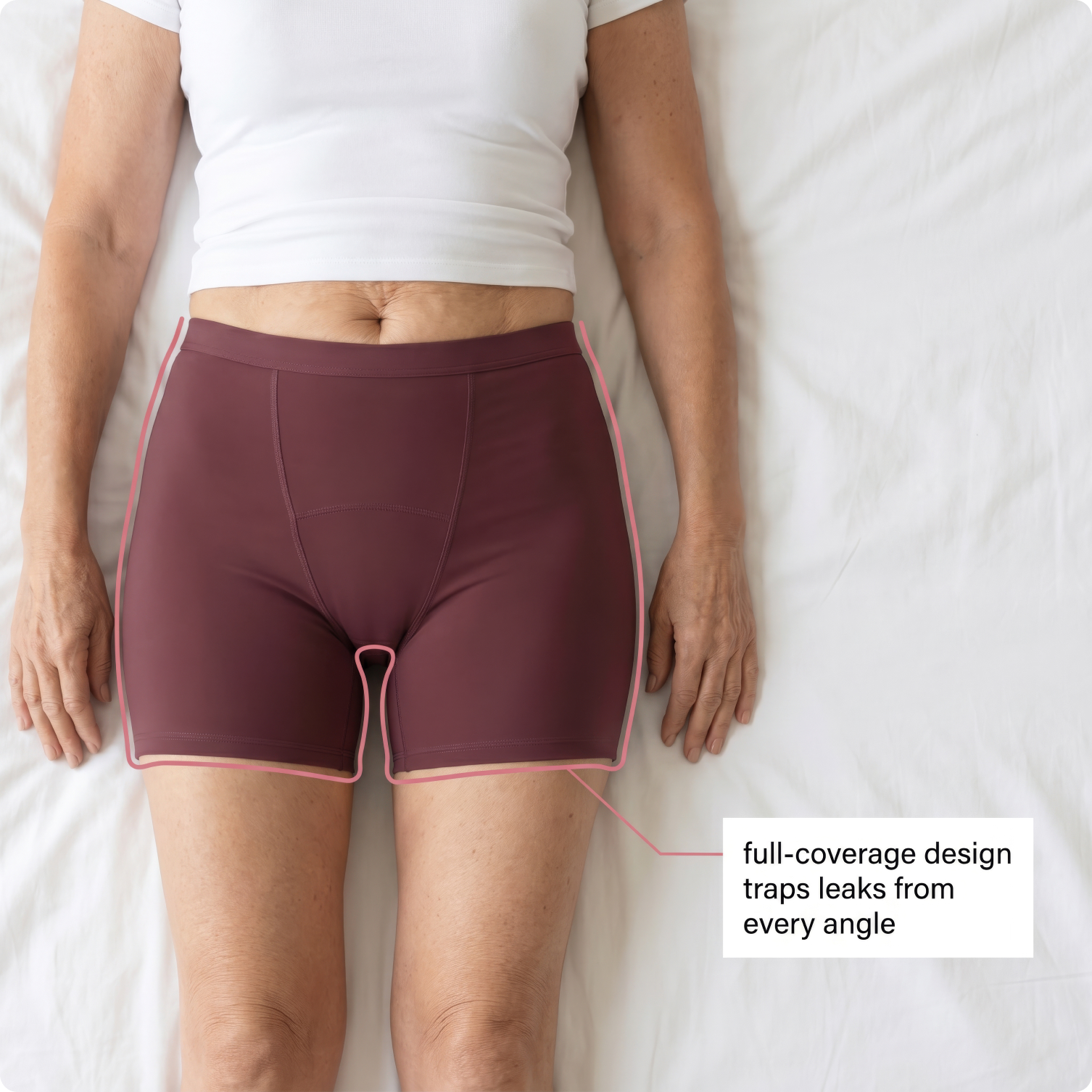 A person lies on a white sheet wearing maroon underwear with a graphic outlining its full-coverage design.