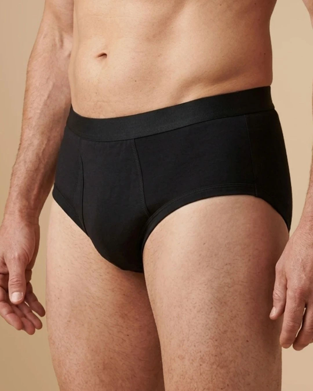 A close-up view of a man from the waist to the upper thighs wearing black briefs.