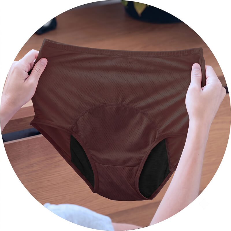 A person's hands holding up a pair of brown, high-waisted, perforated underwear with a black gusset.
