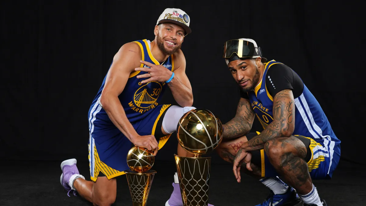 Two basketball players posing with trophies, wearing blue and yellow uniforms.