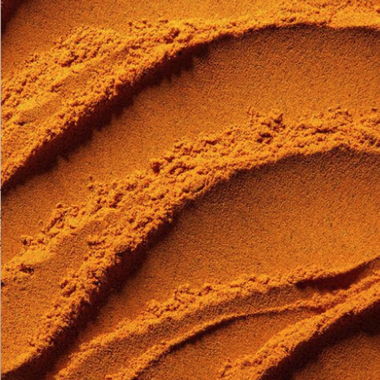Close-up of textured orange powder with wavy patterns.