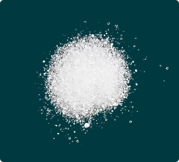 An overhead view of a pile of white, coarse crystals on a dark teal background.