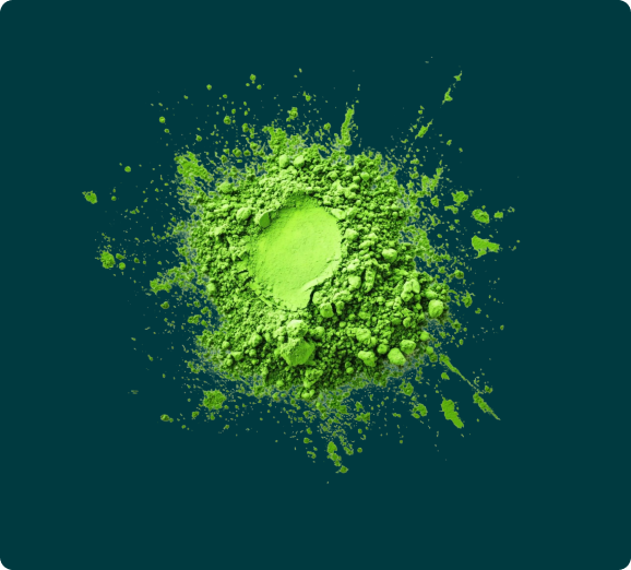 An overhead shot of a pile of vibrant green powder splashed against a dark teal background.