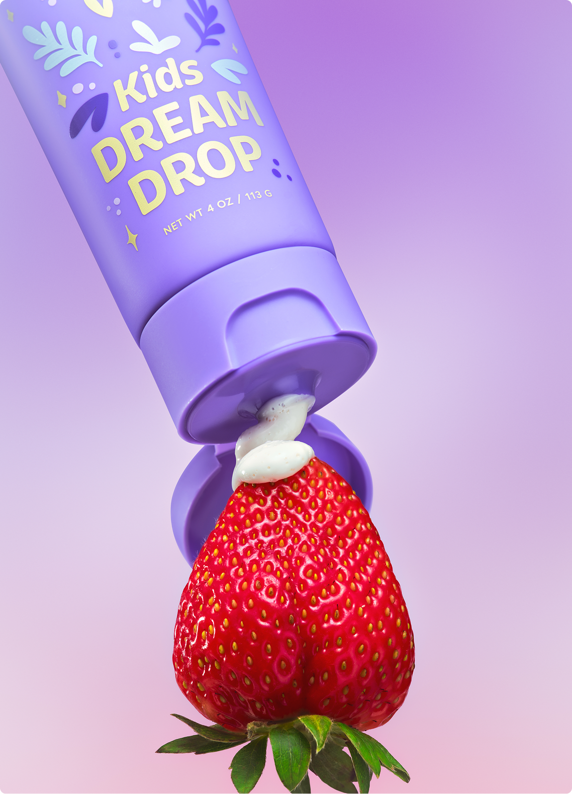 A purple tube labeled 'Kids Dream Drop' squeezes a white cream onto the tip of a strawberry.