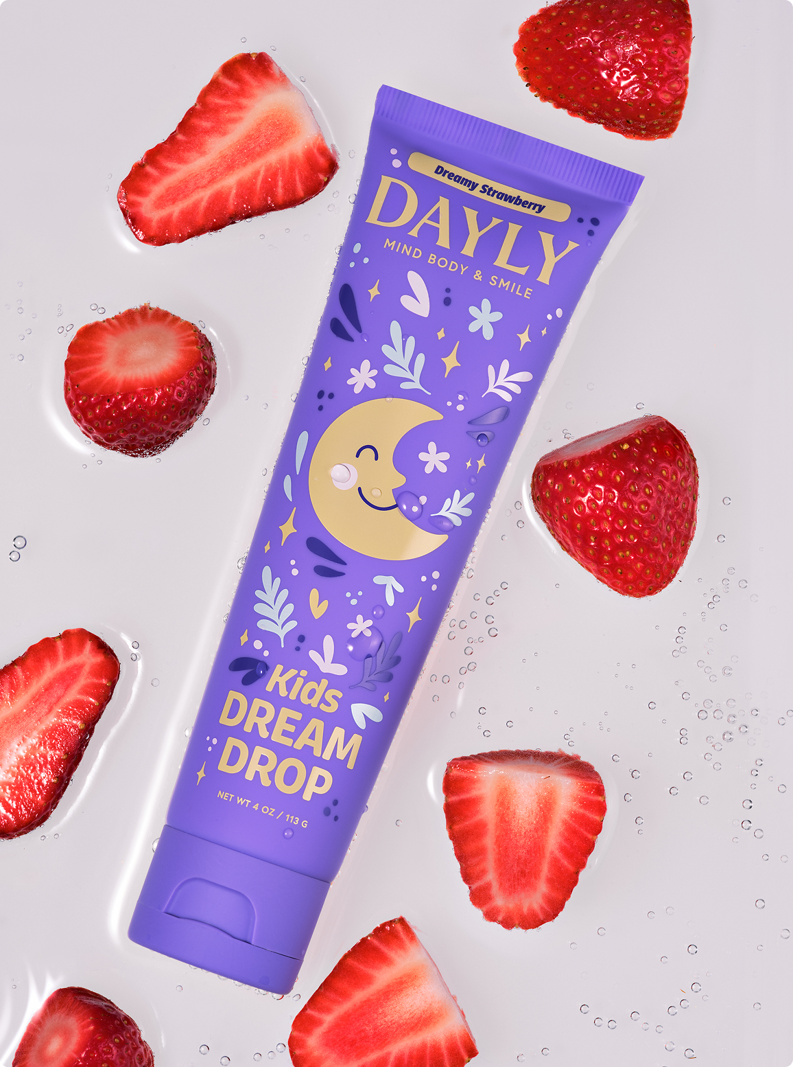 A purple tube of DAYLY Kids Dream Drop, Dreamy Strawberry, surrounded by sliced strawberries in bubbly liquid.