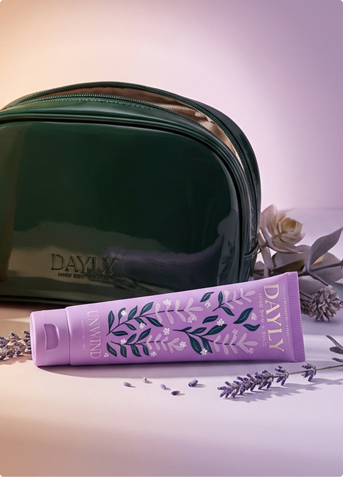 A purple tube of lotion lies in front of a shiny green cosmetic bag with sprigs of lavender.