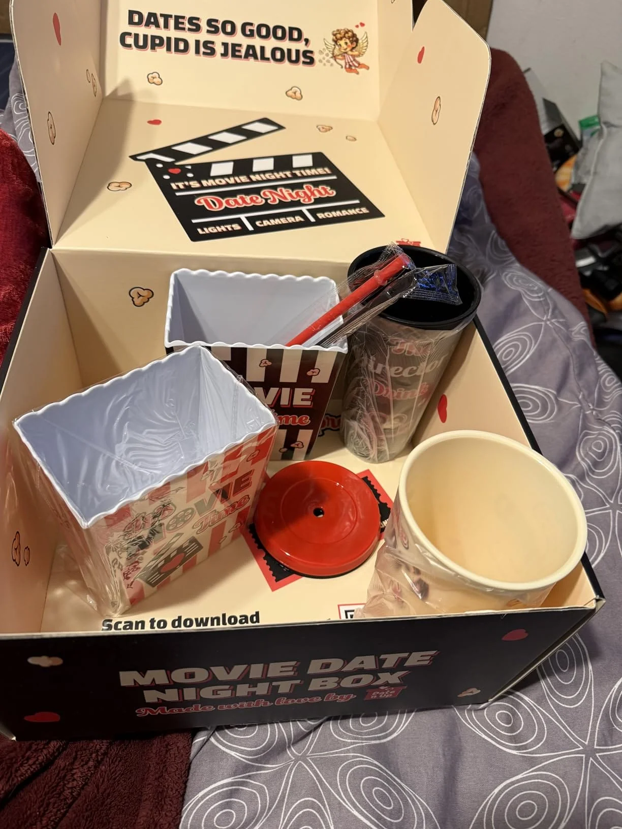 An open 'Movie Date Night Box' kit with popcorn containers, cups, and straws inside.