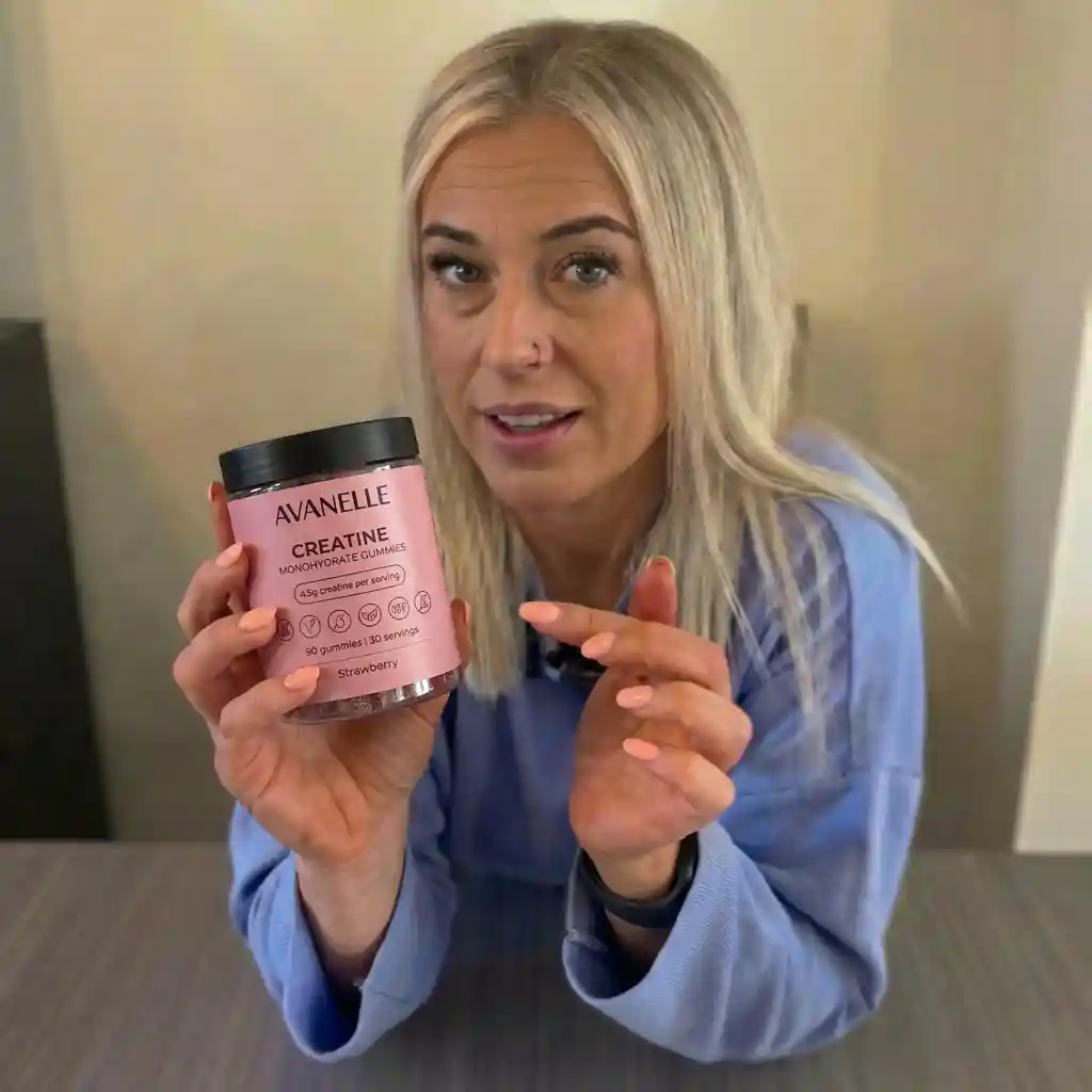 A blonde woman in a blue shirt holds up a pink jar of Avanelle Creatine Monohydrate Gummies.