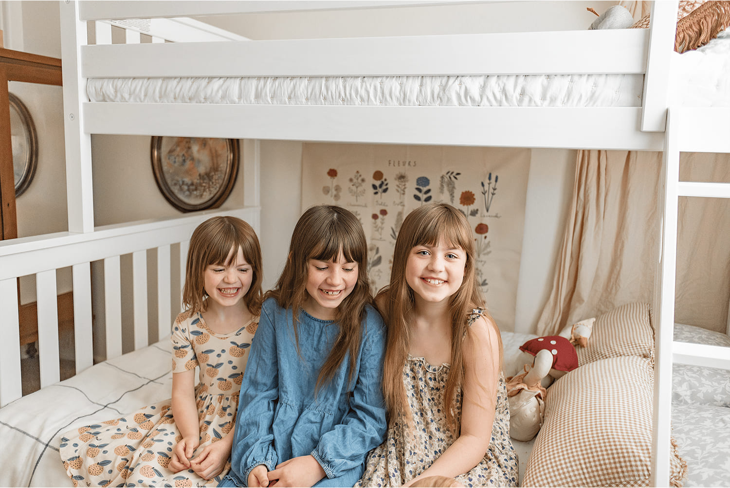 3 little girls smiling, sitting on a white bunk bed