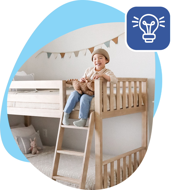 little boy wearing a beanie laying on top wooden bunk with feet dangling over onto ladder.