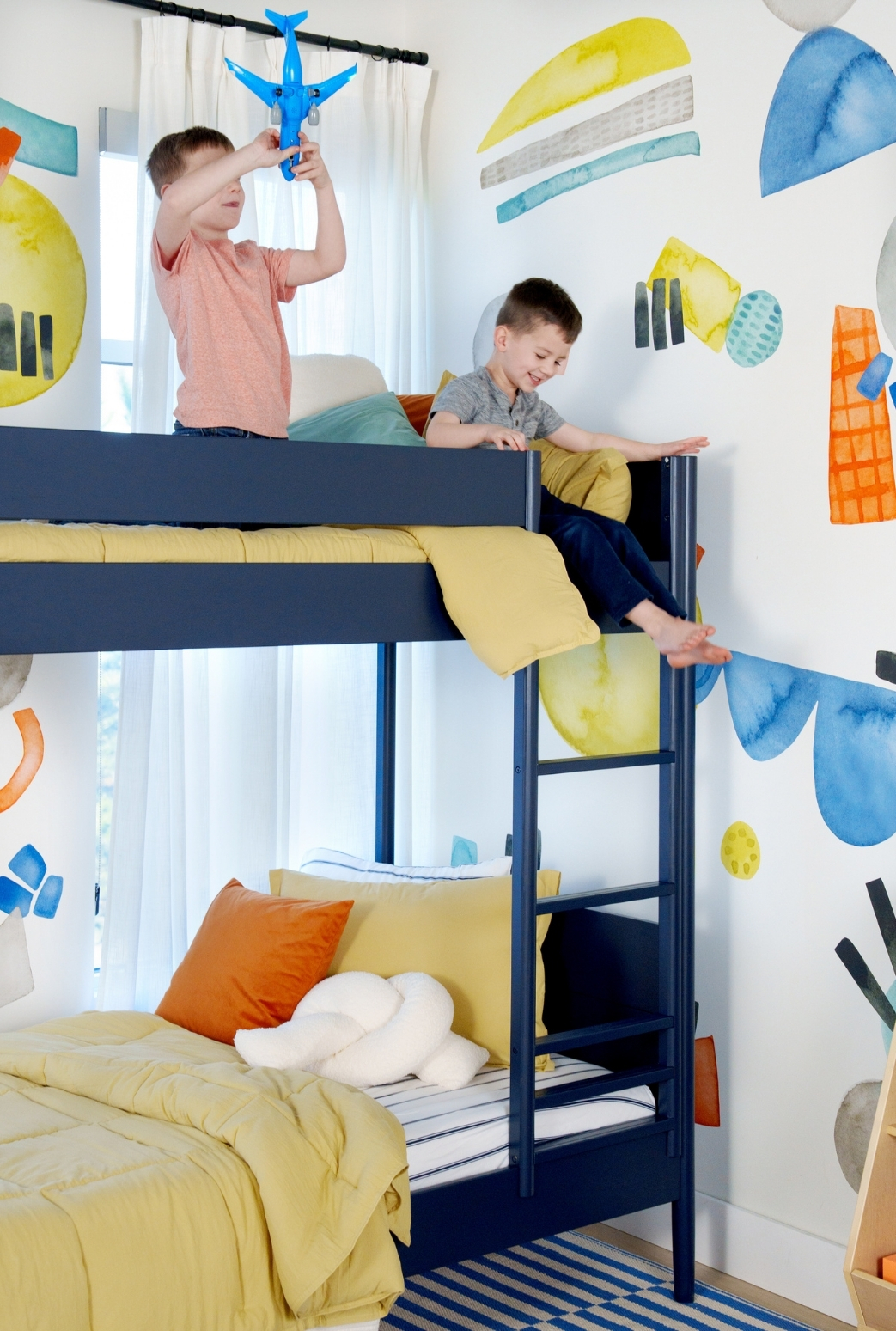 Little boys room with colorful, watercolor wall decals of organic shapes. Playing and exploring in their bunk bed.