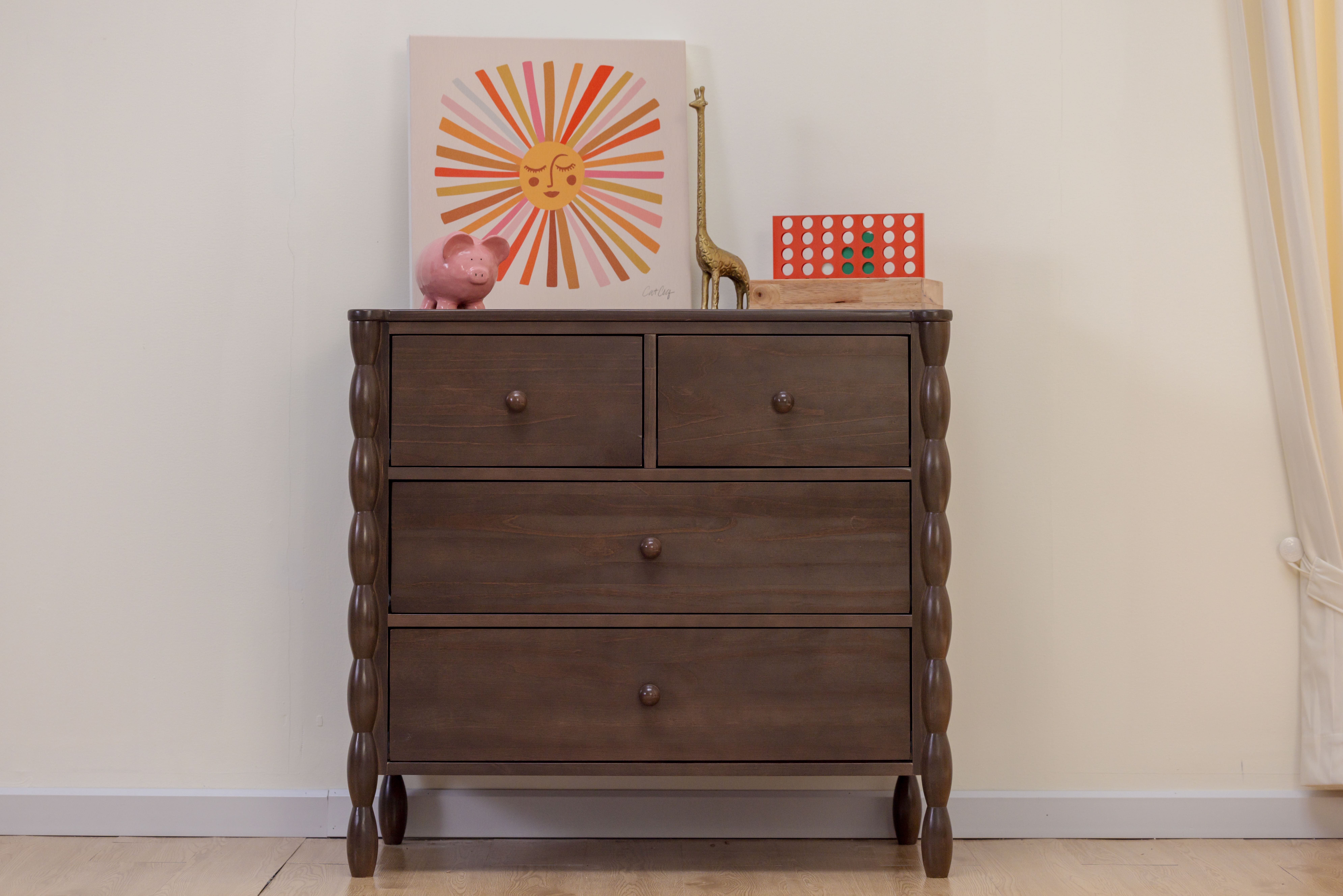 Wooden dresser with artwork, pink piggy bank, and giraffe statue on top.