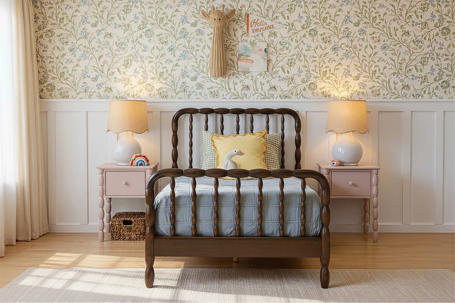 A flower-wallpaper room with Jenny Lind style twin bed with a dark brown finish, and two pink matching nightstands on either side of the bed. Both nightstands have a lamp decor. There is also children's decor on the wall above the bed.
