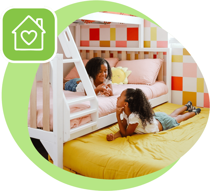 two little girls laying on a white bunk bed, smiling at one another.