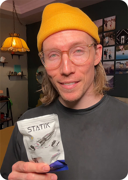 Person in a yellow beanie holding a product package labeled 'STATIK'.