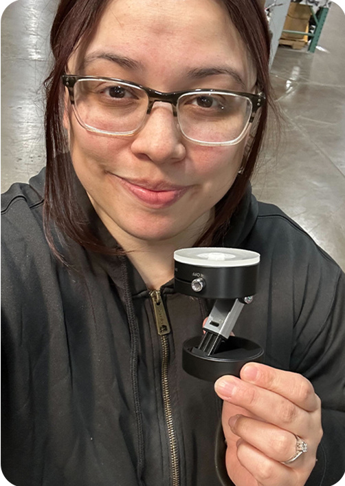 Person holding a small black and white device, smiling at the camera.