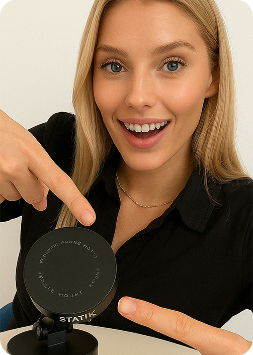 Person smiling and pointing at a phone holder on a table.