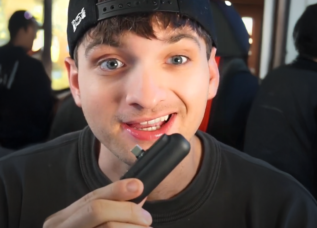 Person holding a small black device, smiling at the camera.