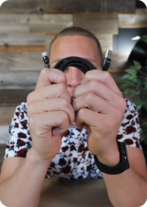 Person holding a coiled black cable with USB connectors.
