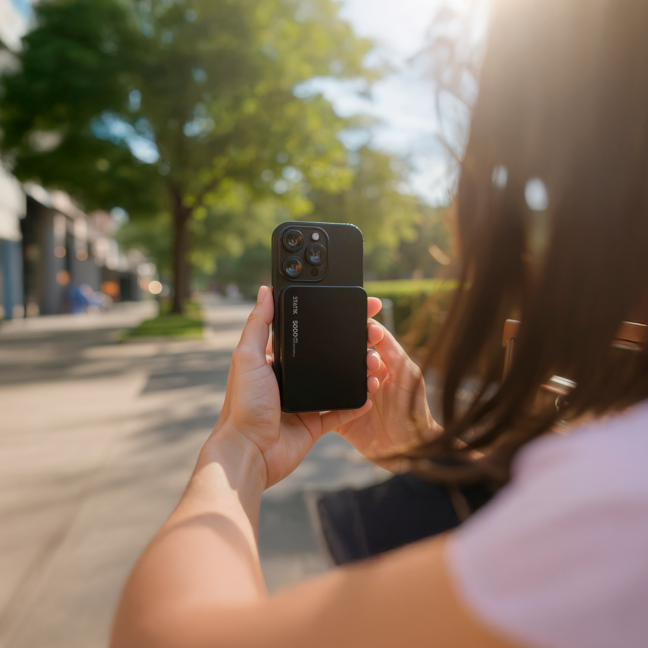 Person holding a smartphone with a camera attachment outdoors.