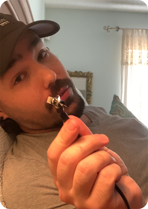 Person using a nose hair trimmer while lying on a couch.