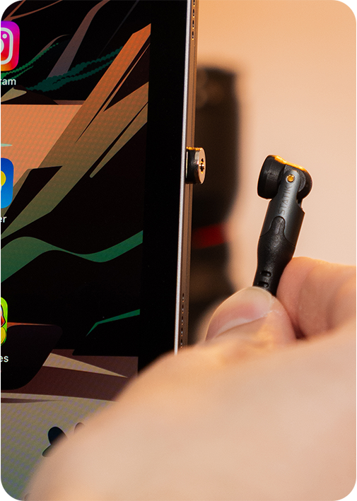 Person plugging a cable into a tablet with colorful app icons.
