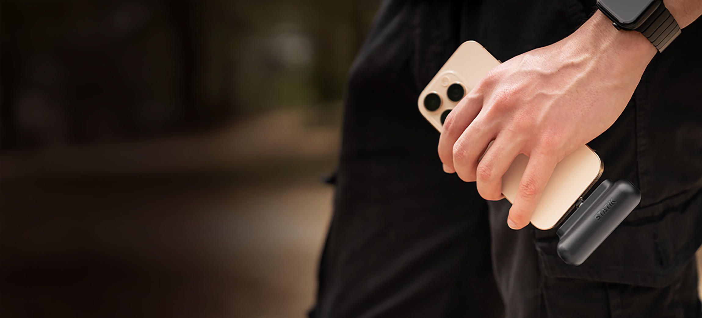 Person holding a smartphone with a black accessory attached.