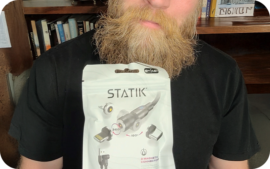 Person holding a Statik magnetic cable package in front of bookshelves.