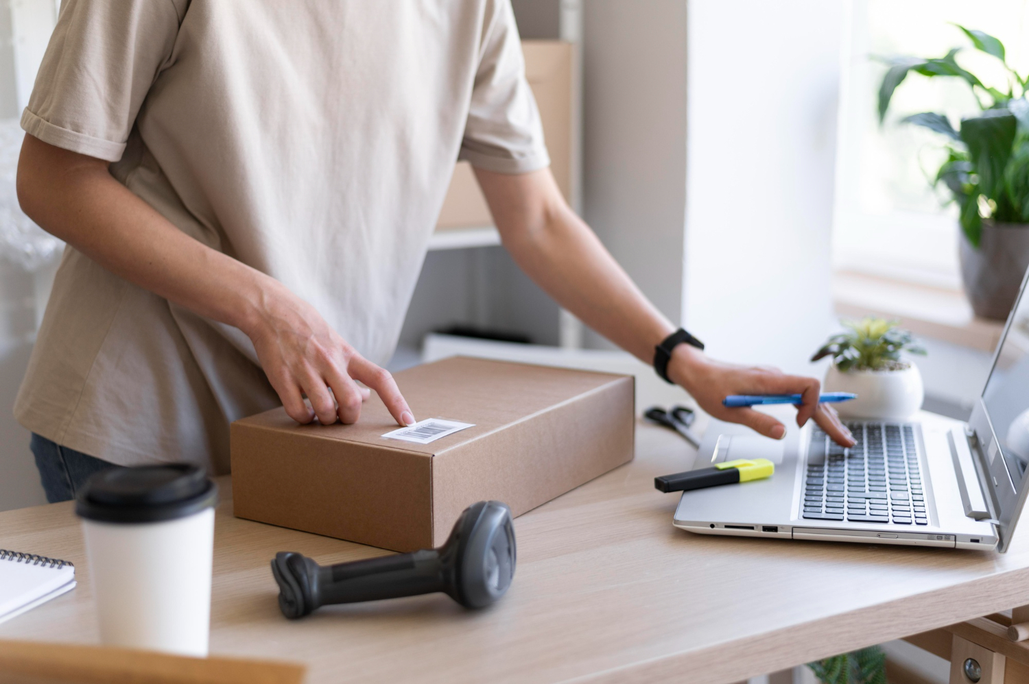 Person using a laptop and pointing at a package with a barcode.