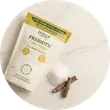 A pouch of prebiotic powder next to a few small brown sticks on a white marbled surface.