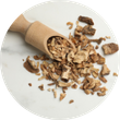 A small wooden scoop filled with dried, chopped mushrooms on a white marble surface.