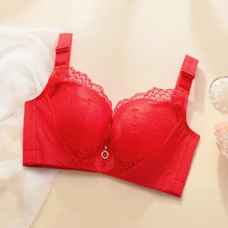 Red lace bra with decorative pendant on a light background.