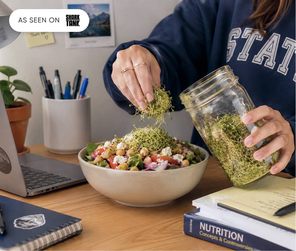 A jar of fresh broccoli sprouts poured over a salad on a dorm desk