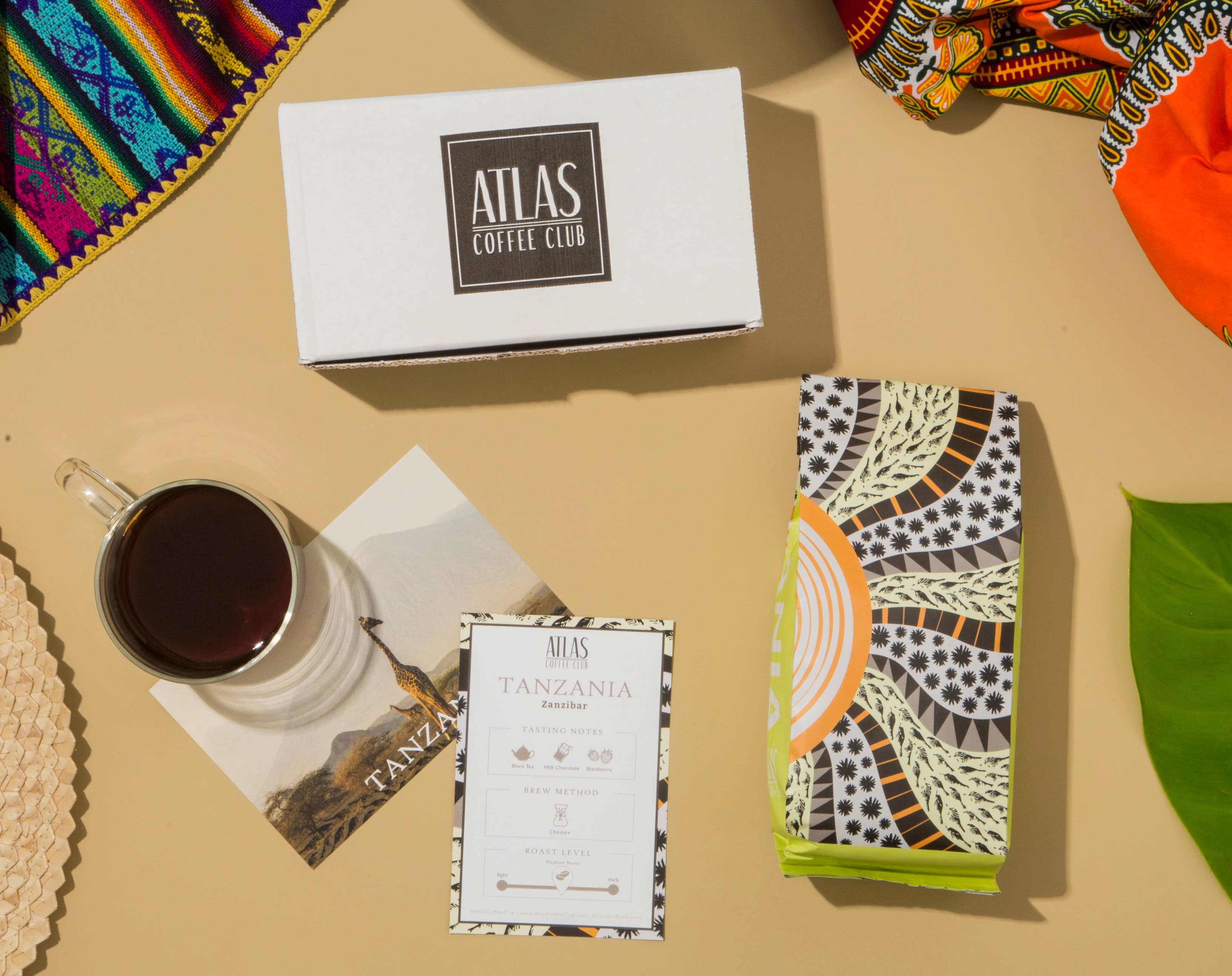 An overhead view of an Atlas Coffee Club box, a bag of coffee, a mug, and several cards.