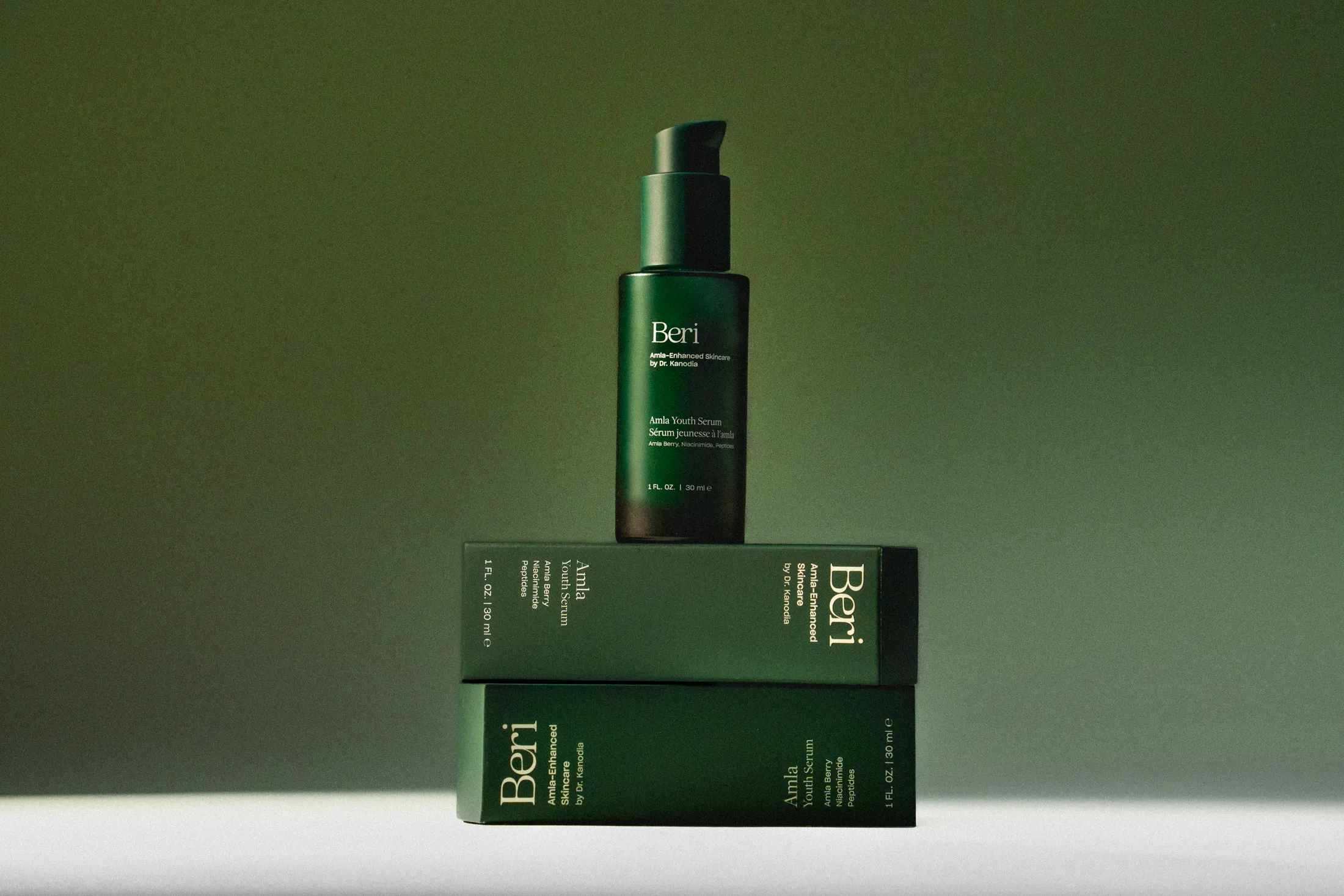 Green skincare bottle on stacked boxes with a gradient background.