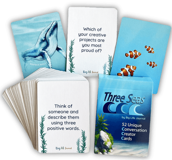 A deck of 'Three Seas' conversation cards with some fanned out showing prompts and ocean-themed illustrations.