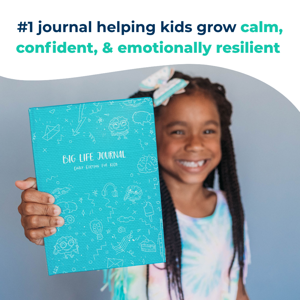 A smiling young girl with braided hair holds up a blue book titled 'Big Life Journal'.